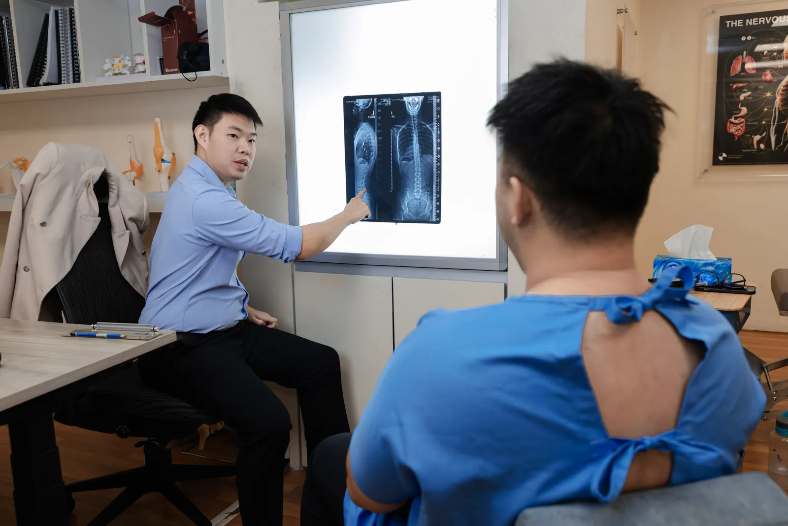 Chiropractor pointing out findings on a spinal X-ray lightbox in Cheras, Maluri, Kuala Lumpur