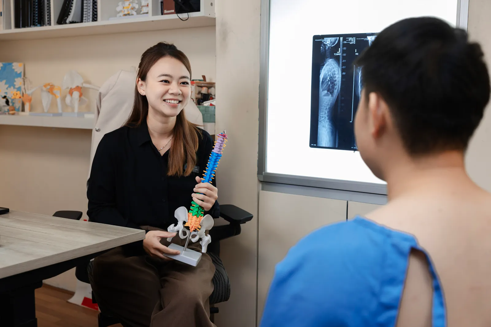 Chiropractor explaining spinal anatomy with a spine model to a patient at Persistence Chiropractic Care in Cheras, Kuala Lumpur