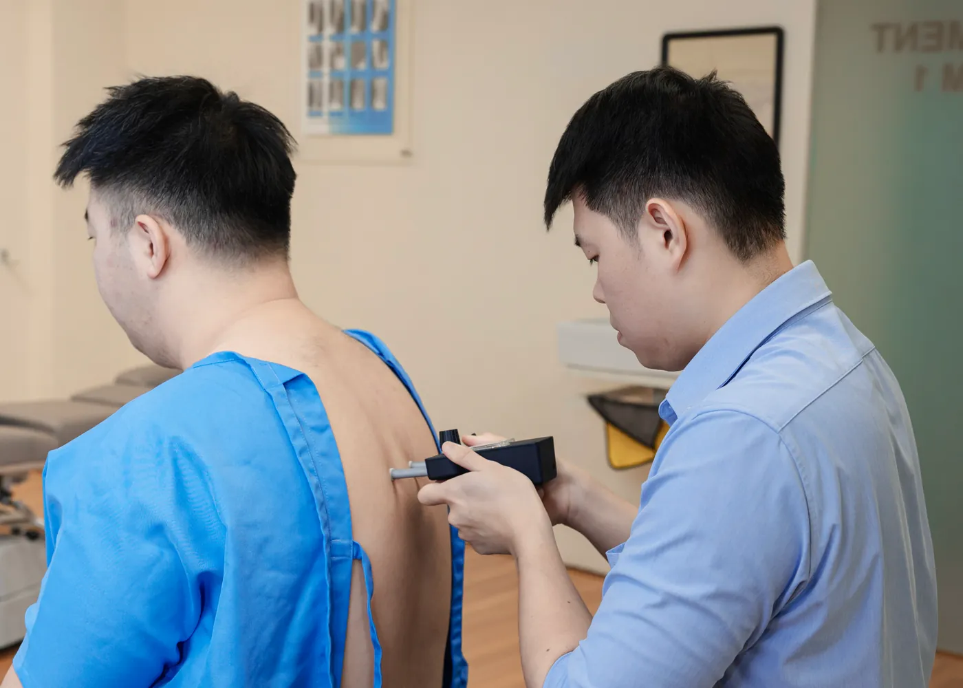 Chiropractor examining a seated patient upper back and posture at Persistence Chiropractic Care in Cheras, Kuala Lumpur