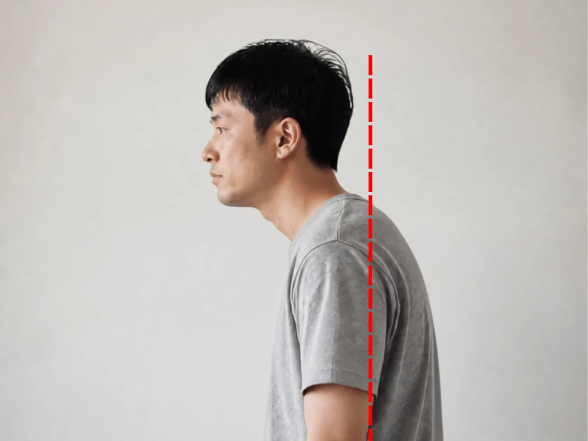 一名站立男子的侧面,头部超出红色垂直参考线,肩膀呈圆拱状